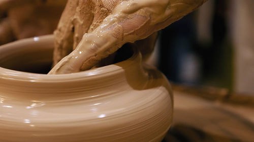 Cropped hands of craftsperson making clay product in pottery workshop