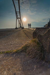 People on shore by sea against sky during sunset