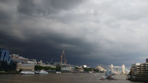 Boats moored at harbor against cloudy sky