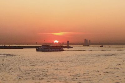 Boat sailing in sea against clear sky during sunset