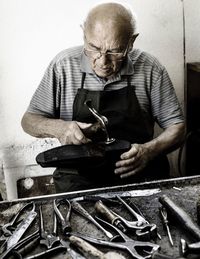 Man making shoe while sitting in workshop