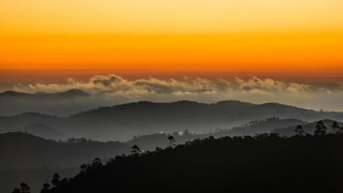 Scenic view of mountains against dramatic sky during sunset