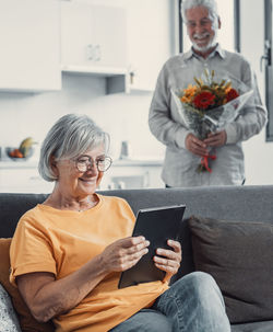 Portrait of woman using digital tablet while sitting on sofa at home