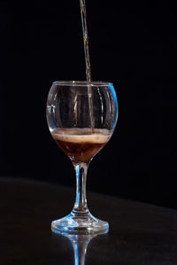 Close-up of wineglass on table against black background