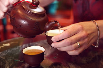 Cropped image of woman pouring chinese tea in cup