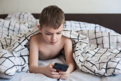 Midsection of boy using mobile phone at home