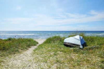 Upside down boat at beach against sky