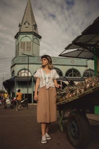 Full length of woman standing by building against sky