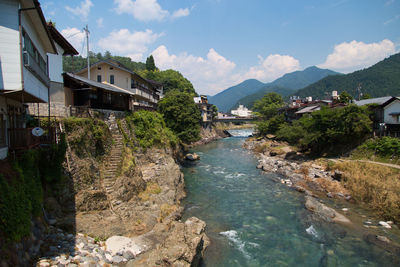 River amidst buildings and mountains against sky