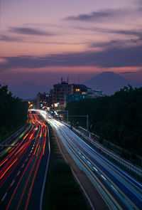 High angle view of light trails on road against sky at sunset