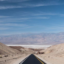 Road leading towards mountains against sky