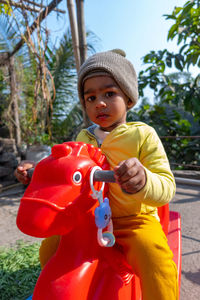 Portrait of cute boy wearing knit hat sitting on toy outdoors