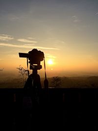 Silhouette person standing on landscape against sky during sunset