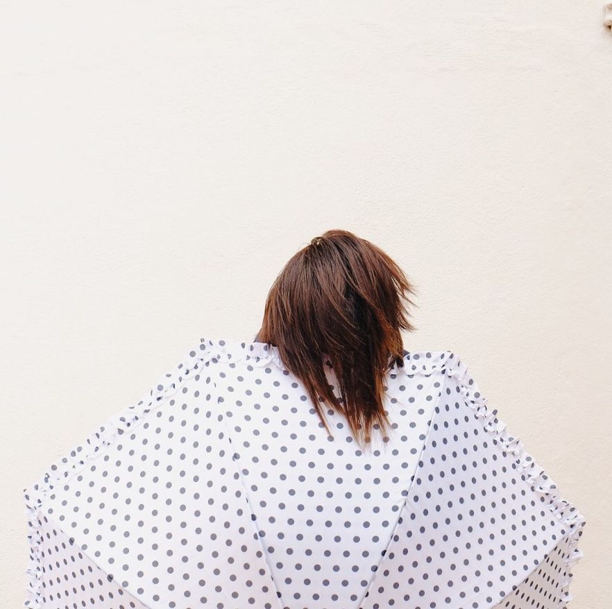 rear view, long hair, leisure activity, lifestyles, copy space, person, indoors, built structure, wall - building feature, pattern, architecture, standing, full length, brown hair, day, waist up, wall, clear sky