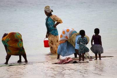 Women working by girls at beach