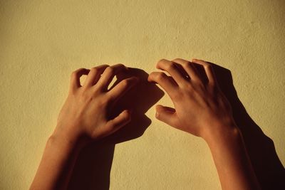 Cropped hands of woman against wall