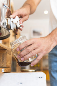 Male entrepreneur pouring honey in jar at shop