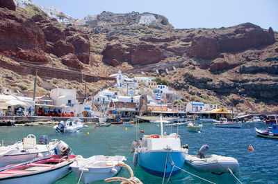 Sailboats moored at harbor by mountains against sky