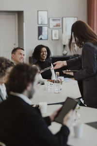 Smiling business professionals discussing over digital tablet in education class
