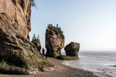 Rock formation on beach against clear sky