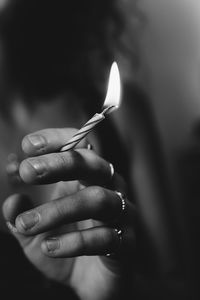 Midsection of woman hand holding lit candle