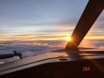 Airplane wing against sky during sunset