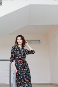 Portrait of young woman standing against wall