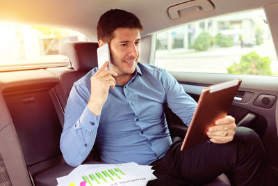 Young man using mobile phone while sitting in car