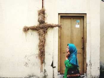 Side view of woman against wall in building