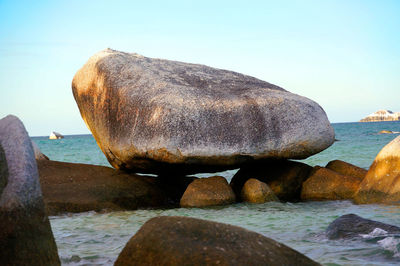 Close-up of sea by rocks against clear sky