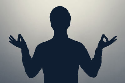 Silhouette man with arms raised against white background