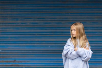 Young woman standing against blue wall