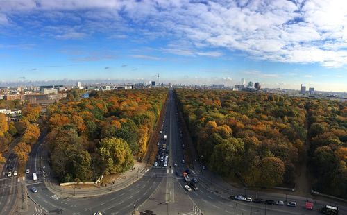 Road amidst trees in city against sky