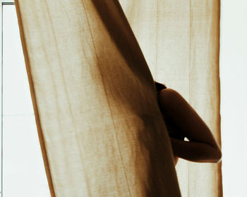 Close-up of woman standing by curtain at home