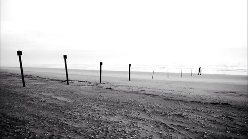 Poles at beach against clear sky
