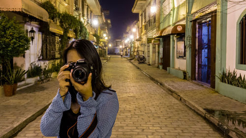 Full length of woman photographing on street in city