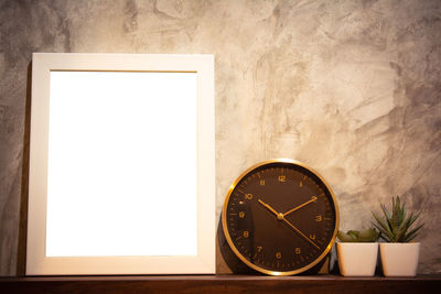 Close-up of clock on table against wall