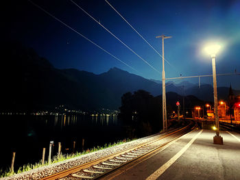 Illuminated railroad tracks against sky at night