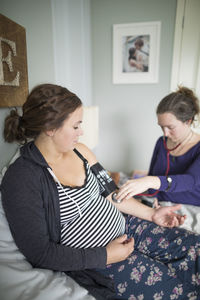 Midwife examining pregnant woman at home