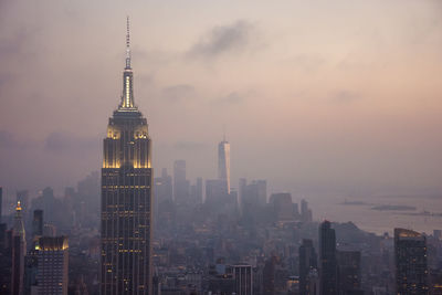 Illuminated buildings in city against sky during sunset