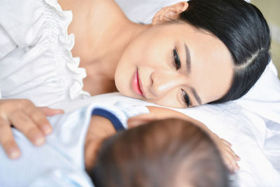 Mother relaxing with baby boy on bed at home