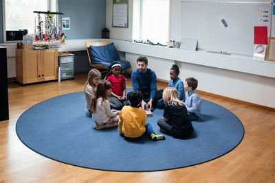 Teacher playing with students while sitting on floor at school