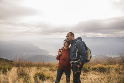Mature couple with backpacks standing on mountain