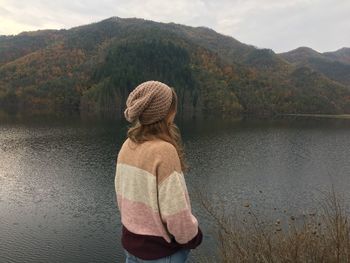 Rear view of woman standing by lake