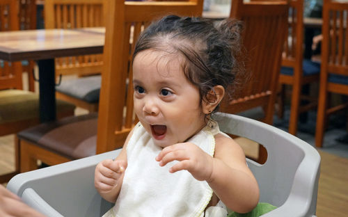 Baby girl sitting in high chair at home