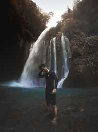 Full length of young man standing by waterfall