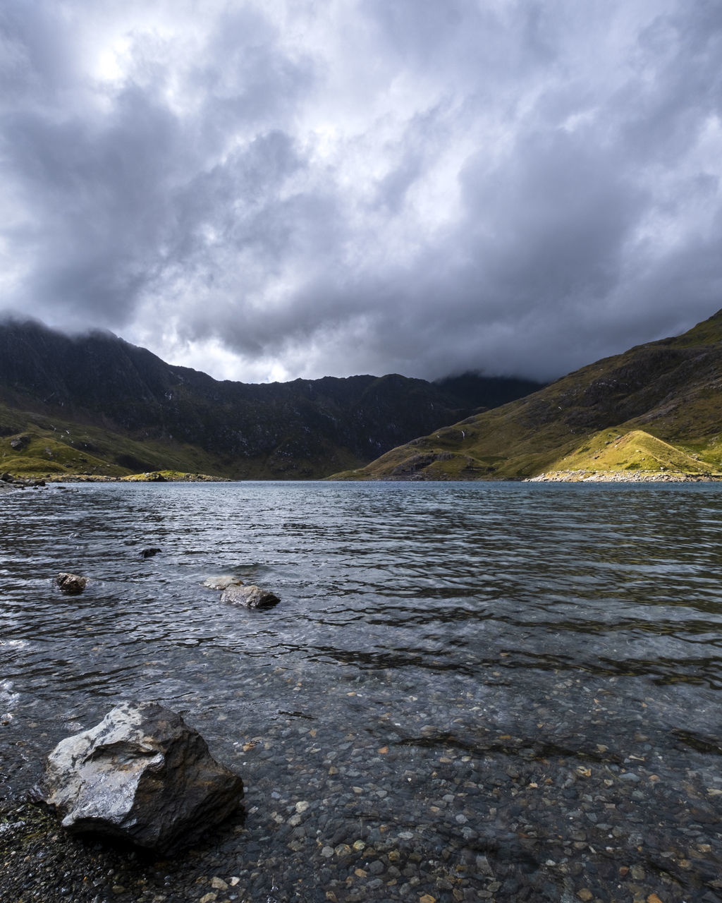 lake, mountain, cloud, nature, water, sky, environment, scenics - nature, wilderness, landscape, beauty in nature, highland, land, reflection, no people, shore, mountain range, rock, coast, overcast, body of water, travel, travel destinations, outdoors, tranquility, dramatic sky, non-urban scene, tranquil scene, day, storm cloud, storm, tourism