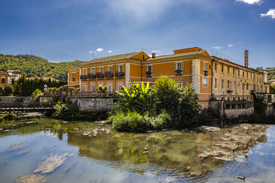 Buildings by river against sky