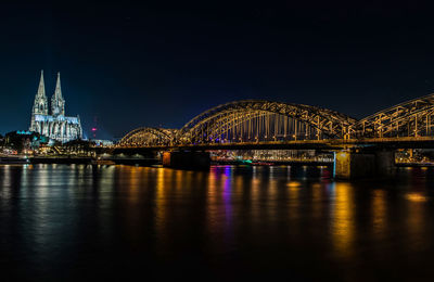 Illuminated bridge over river at night