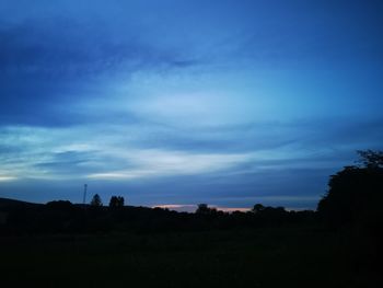 Silhouette trees on field against sky at sunset